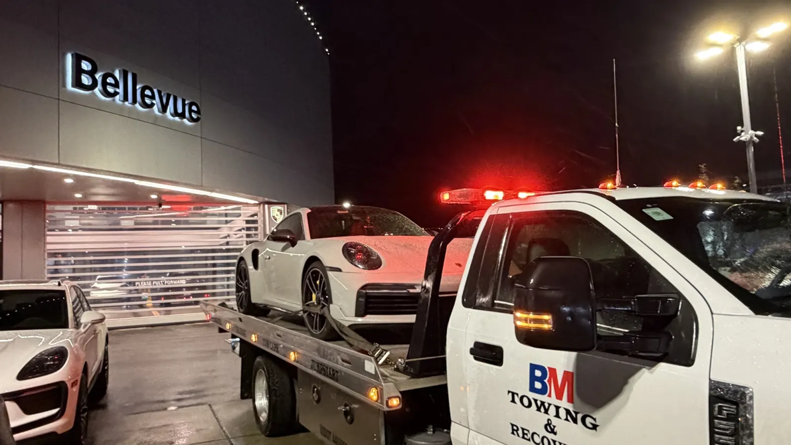 BM Towing flatbed loading a Porsche at the Bellevue dealership