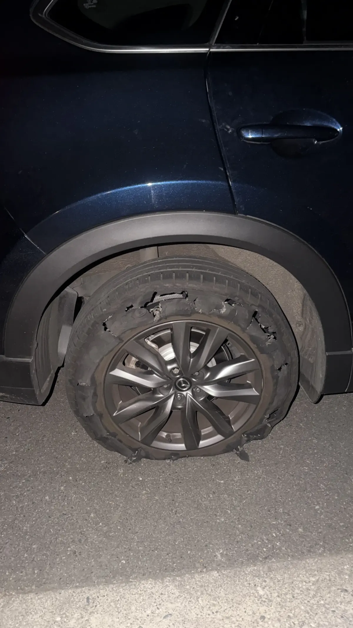 Severely shredded rear tire needing roadside tire-change assistance
